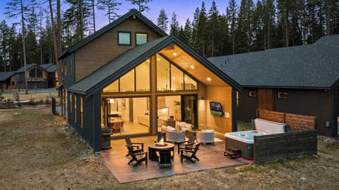 Back patio with hot tub, firepit, and outdoor lounge overlooking the open meadow.