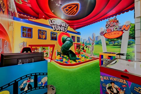 Enter a lively playroom filled with colorful Looney Tunes murals and whimsical decor. The cheerful furnishings and soft grass-like carpet create a fun atmosphere where kids can dive into endless adventures and play.