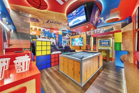 Step into a vibrant game room that sparks joy with its bold colors and playful decor. A pool table invites friendly competition, while multiple screens create the perfect backdrop for movie nights or sports events.