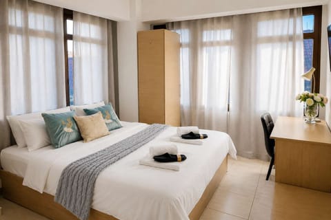 Cozy and bright studio bedroom featuring a comfortable double bed, soft linens, and large windows that fill the space with natural light.