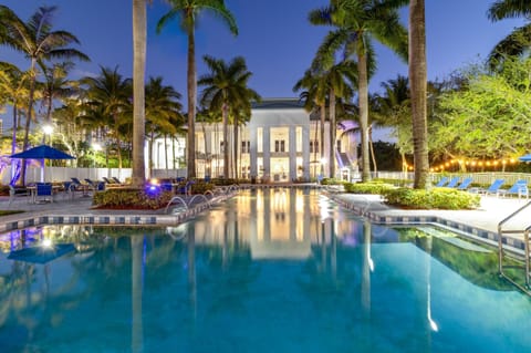 Relax in a stunning palm-lined resort pool, beautifully illuminated at night for a true tropical escape.