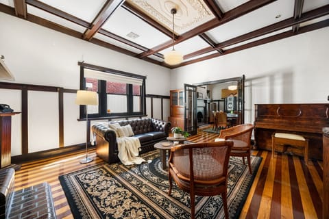 The elegant formal living room features a grand piano and classic furnishings that reflect the home’s heritage charm.