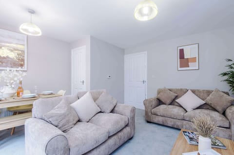 Relax in a stylish living space with plush sofas, soft tones, and a cozy dining area. Perfect for unwinding or sharing meals, this modern retreat blends comfort and charm for a memorable stay.