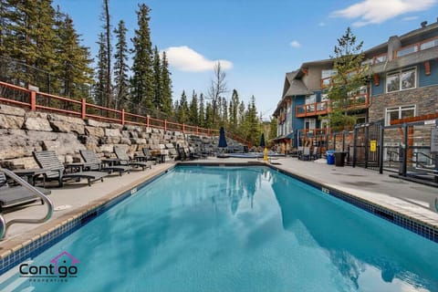 Resort-style outdoor pool with sundeck lounge chairs — the ultimate family vacation amenity steps from Kananaskis Country, Canmore, AB.