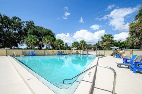 Sparkling pool area w/ lounge chairs & palm trees, perfect for a refreshing afternoon swim