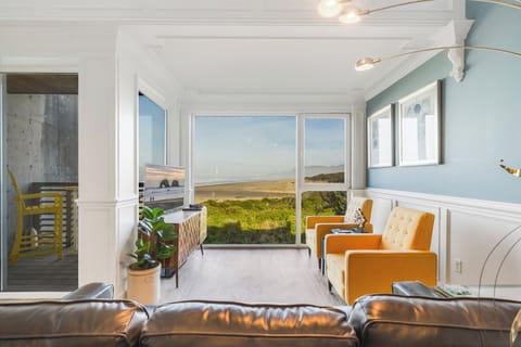 Bright oceanview living room with wall-to-wall windows and cozy seating overlook