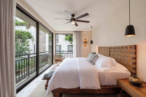 A calm and comfortable bedroom with large windows and a private balcony view.