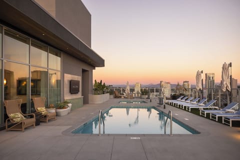 The rooftop shared pool deck transforms into an ambient oasis as the city lights come up.