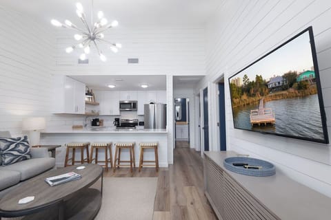 Living Area/Kitchen - This cozy duplex unit is setup to utilize every square inch of space. The open living area flows seamlessly into the kitchen with dining in between  at the open bar. The large mounted television offers entertainment during your down time.