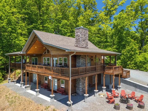 Cabin Exterior – Side and Front with Fire Pit - Side and front cabin view showing the two-level deck, stone chimney, and fire pit area.