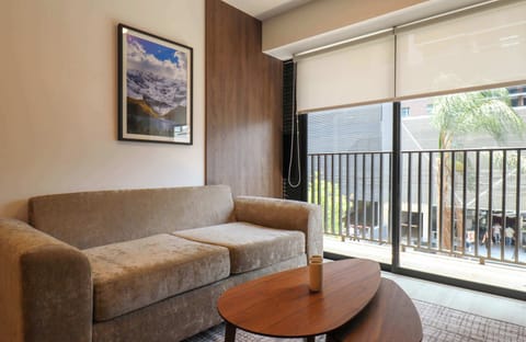 Cozy living area with sofa and coffee table, bright with natural light from the balcony.