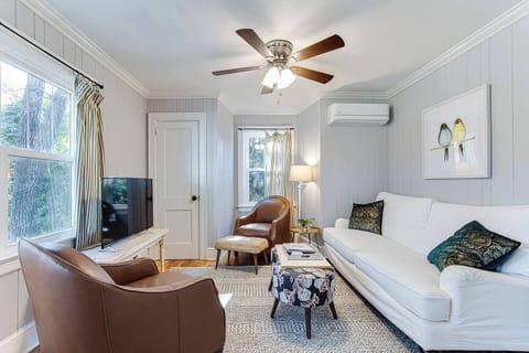 Cozy living space with a full dining table, comfortable sofa, Roku tv with streaming channels, and large picture window overlooking the neighborhood.
