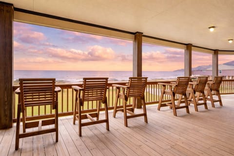 Covered beachfront deck with wooden chairs and outdoor seating overlooking the Gulf coast at Crystal Beach, perfect for relaxing and enjoying ocean views.