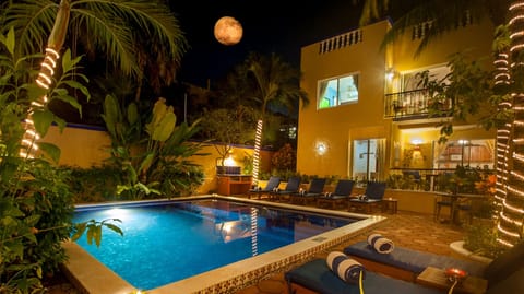 Abbey del Sol – Pool & Gardens at Night - Evening view of the tropical pool area with lounge chairs, warm lighting, and lush gardens—perfect for a relaxing dip after the beach.