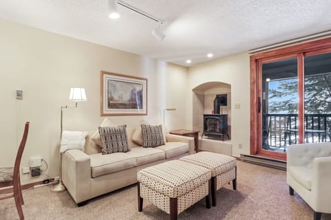 Sink into plush seating by your crackling fireplace, where snowy mountain views frame perfect winter evenings through expansive windows.