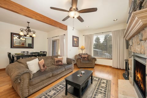 Sink into plush leather sofas by your crackling stone fireplace, where rustic beams and warm lighting create the perfect mountain retreat atmosphere at Granby Lake Shore Estates Townhome 5.