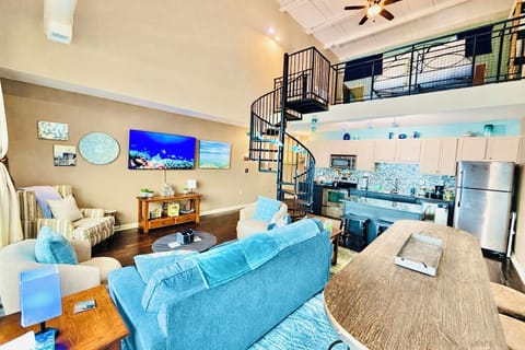 Bright, open living area with soaring ceilings, spiral staircase, and loft above. Comfortable seating flows seamlessly into the kitchen—perfect for relaxing together after a day exploring downtown Sandusky.