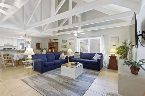 Relax in your spacious living room featuring exposed white beams, navy sectional seating, and coastal touches throughout this bright, airy space.
