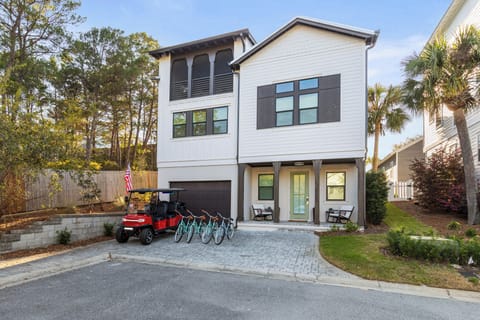 Modern coastal home features stylish exterior with convenient golf cart and bikes for exploring the area.