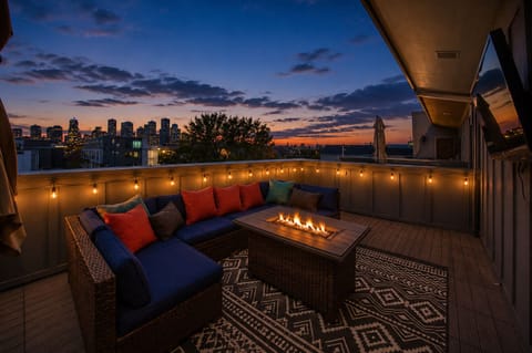 Sunset rooftop lounge with fire table, string lights, and skyline views