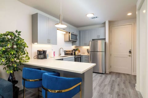 Compact kitchen fully stocked with all essentials and sleek stainless steel appliances—everything you need in a cozy space.