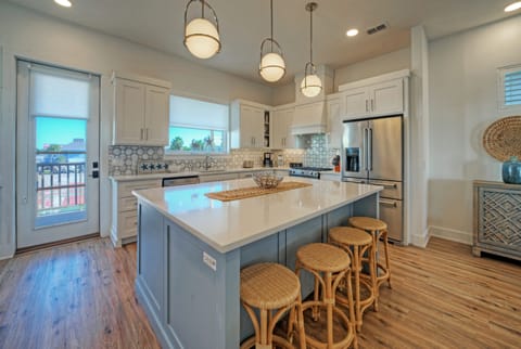 Modern kitchen with a large blue island, white cabinetry, and pendant lighting. (Southern Cross)