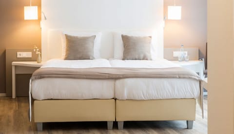Unwind in crisp linens beneath soft, calming bedside glow.