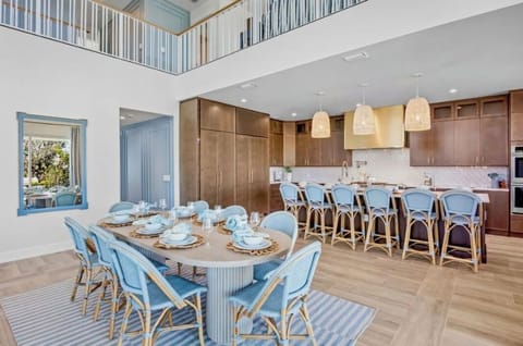 Your spacious open-plan kitchen and dining area features coastal blue accents, warm wood tones, and soaring ceilings perfect for memorable meals together.