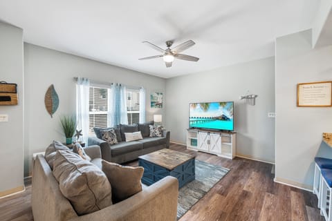 Sink into plush sofas and unwind in your bright, coastal-themed living room with tropical décor and modern entertainment setup.