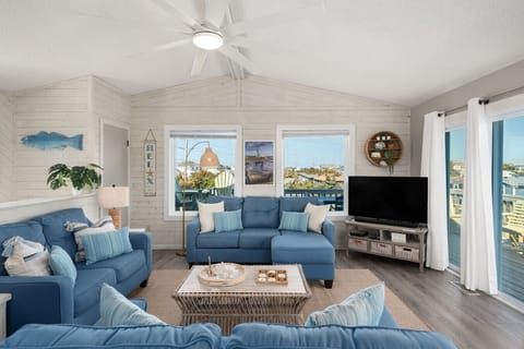 Bright living room w/ comfy seating, TV & large windows letting in plenty of natural light