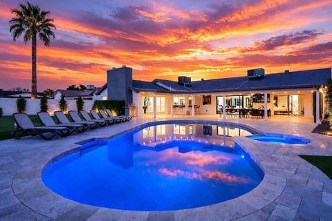 Resort-style backyard with a sparkling pool and hot tub, sun loungers, cozy outdoor seating, fire pit, mini golf, and cornhole, plus a covered patio with outdoor dining, bar seating, and a Smart TV.