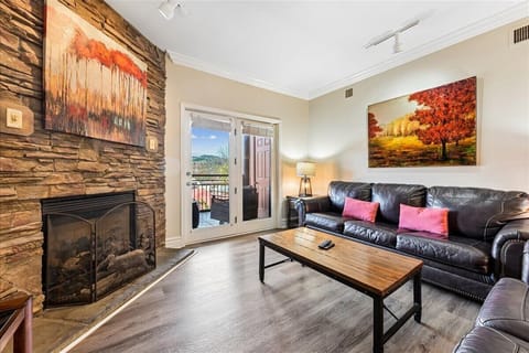Sink into your plush leather sofa by the stone fireplace, where warm artwork and balcony views create the perfect retreat.