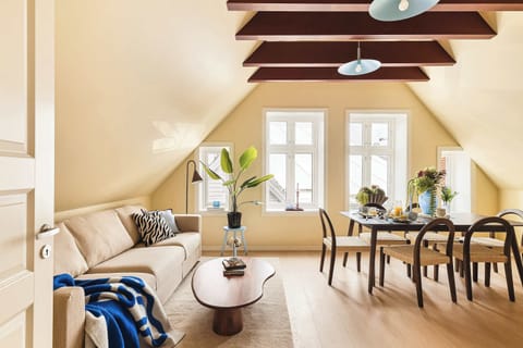 Open-concept living and dining space with natural light and charming wooden beams.