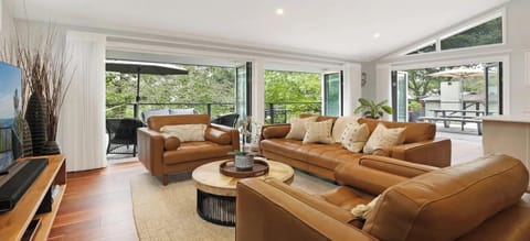 Arcadia Cottage | Living area in open plan room with kitchen and dining area | Back doors open onto beautiful uncovered deck with lounges and alfresco dining | Smart TV with Sonos soundbar | Central ducted heating throughout property