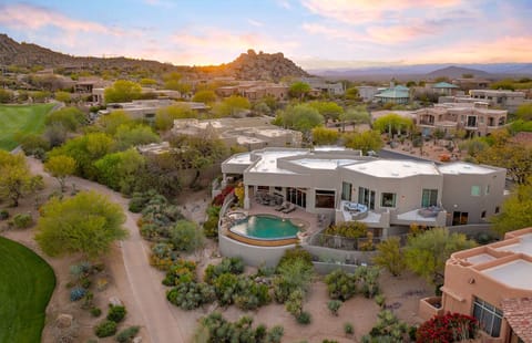 Aerial view of the property showing the curved backyard pool, surrounding desert terrain, and nearby walking trails.