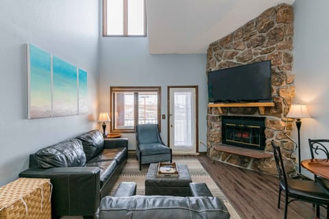 Unwind in your spacious living room at 643 SilverCreek Inn featuring plush leather seating and a cozy stone fireplace perfect for relaxing evenings.