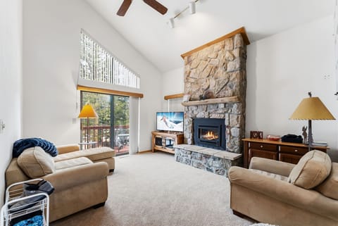 Unwind in your spacious living room with soaring ceilings, cozy stone fireplace, and mountain views from your private balcony.
