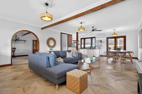 Settle into the main living area where a generous L-shaped sofa faces the TV and wood-burning heater, creating a cosy place to unwind after a day exploring nearby Seaford, Moana and Port Noarlunga beaches.