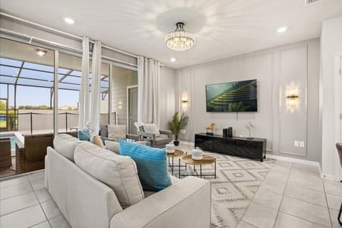 GATHERING ROOM:  Living Room Area with Sofa, 2 Chairs and 65” Flat-Screen TV and Direct Access to Pool / Courtyard