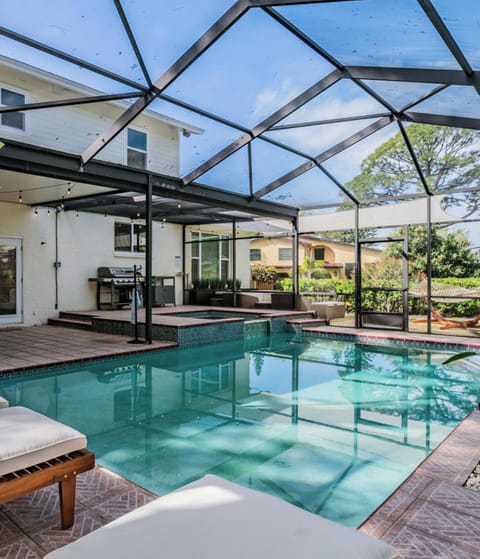 Bask in your private screened pool oasis with spa, lounge seating, and alfresco dining under soft string lights, perfect for sun-soaked afternoons and relaxed evenings after the beach.