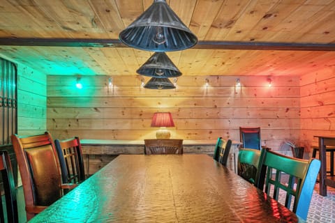 A captain’s view from the head of the mess hall table. Industrial pendant lights align over the hand-scraped wood grain, splitting the space into vivid starboard green and port red zones for an unforgettable, immersive dining experience below deck.