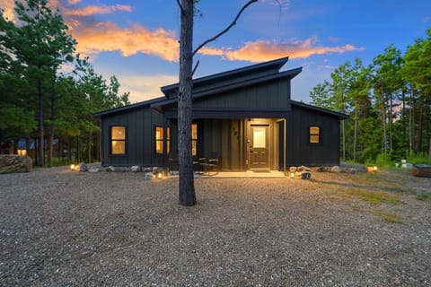 Twilight exterior of The Animal Crossing surrounded by tall Broken Bow pines.