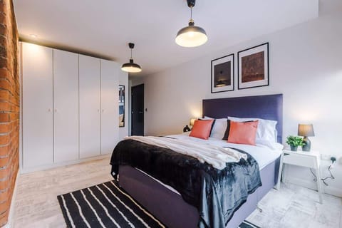 Spacious and beautifully designed bedroom with a king  bed, soft linens, and an industrial touch through exposed brickwork. Enjoy natural light and city views through large windows—perfect for a restful night’s sleep.