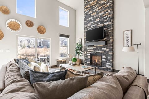 Sink into plush sectional seating while the stone fireplace crackles nearby. Your mountain retreat features soaring ceilings, artistic touches, and windows framing serene views.