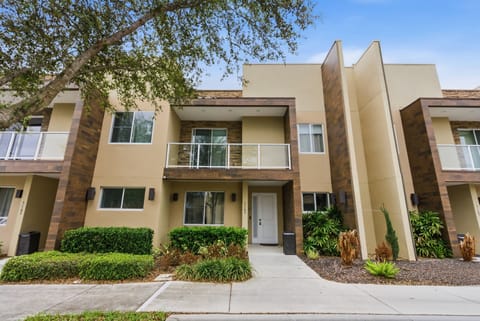 Experience a warm and inviting exterior with rich earth tones and bright white accents, surrounded by lush greenery. Relax on the charming balcony or in the spacious front entry, ideal for enjoying your morning coffee.