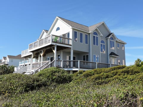 Coastal vacation home with multiple decks and natural dune vegetation, nestled in a peaceful beach community.
