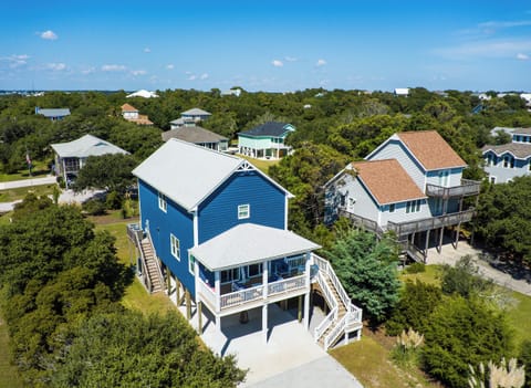 Charming blue beach house nestled among coastal trees in a peaceful residential neighborhood with convenient parking and elevated deck access.