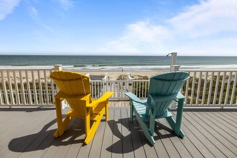 Unwind in colorful Adirondack chairs on your private deck, where ocean waves and endless beach views create the perfect coastal escape.