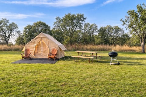 Spacious luxury glamping tent with picnic table, BBQ grill, and fire pit for cozy evenings