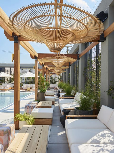 Covered poolside seating with wood pergola and hanging woven shades